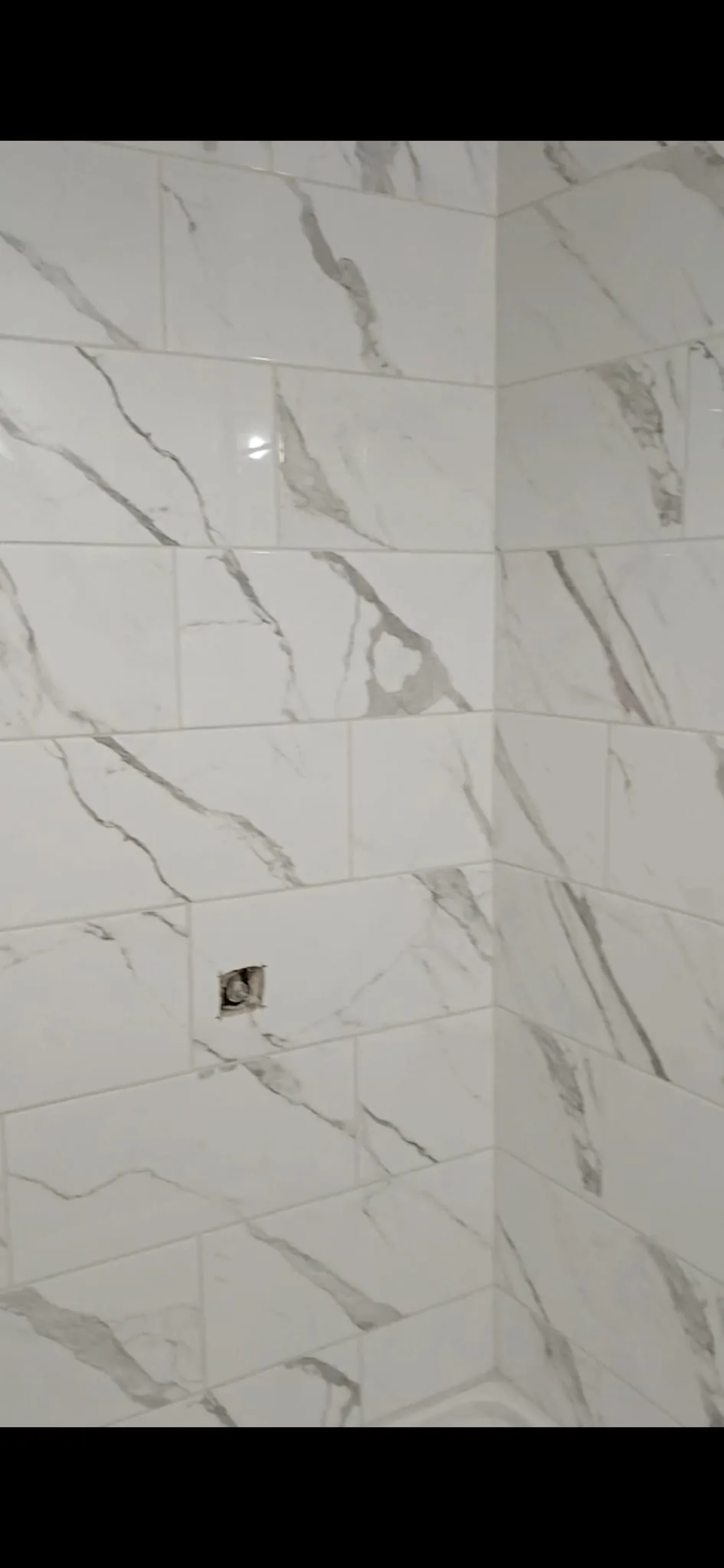 Marble-look tile shower walls set with tight joints